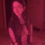 Esther közeli portréja rózsaszín hangulatfényben a LinDom Massage budapesti szalonjában, diszkrét szemkitakarással.